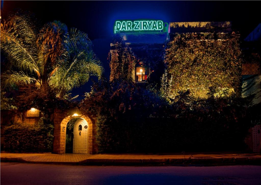 a building with a green street sign on it at night at Riad Dar Ziryab in Fès