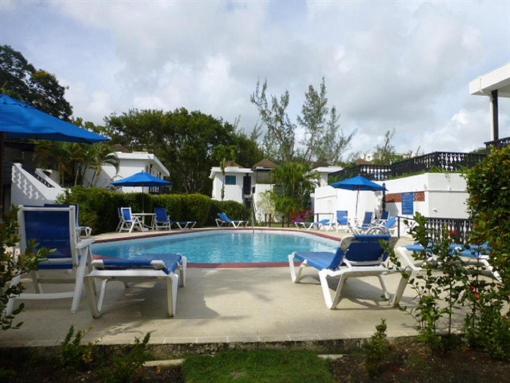 a pool with blue and white chairs around it at Rockley Golf Club, 2 bed 2 bath Pool, Tennis, Golf, Bar & Restaurant! in Bridgetown