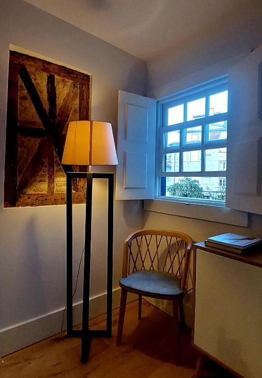 a lamp in a room with a chair and a window at Retiro Studio 34 in Guimarães