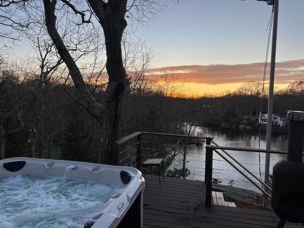a hot tub on a deck with a view of a river at Waterfront Lakehouse Getaway in Clinton with HOT TUB in Clinton