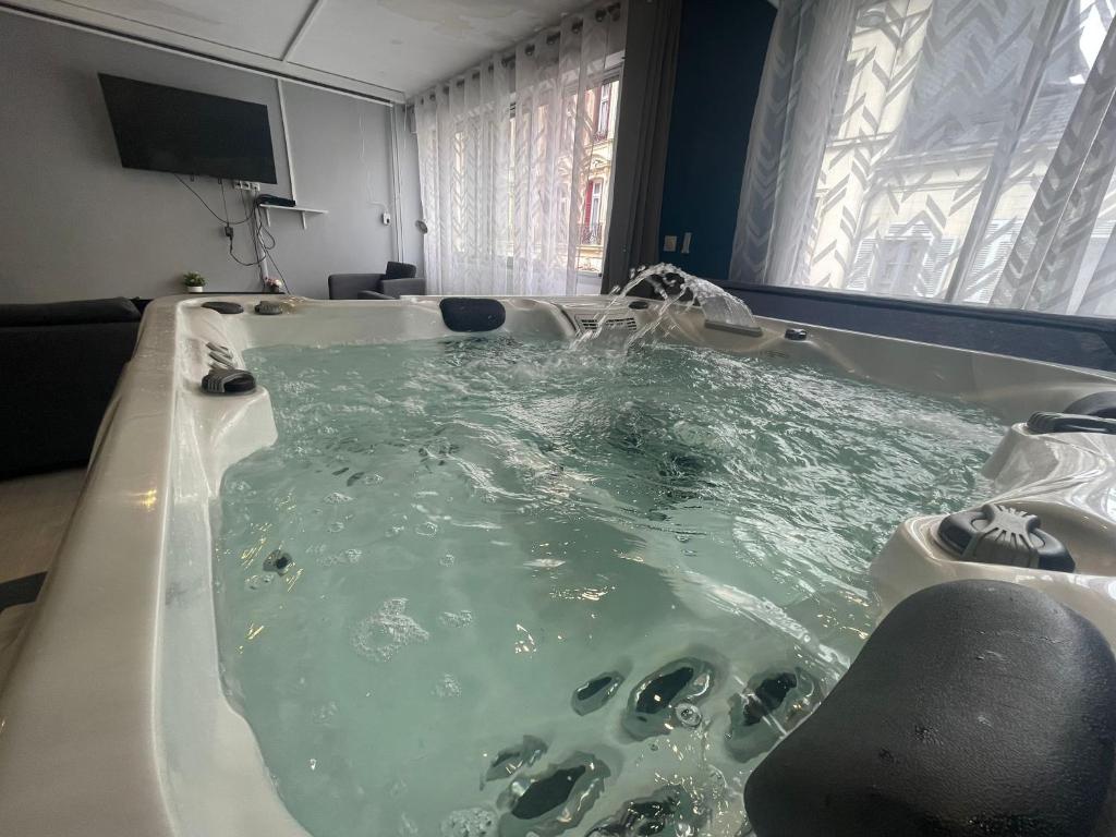 La salle de bains est pourvue d'une baignoire remplie d'eau verte. dans l'établissement Résidence Relaxante Jacuzzi - 041, à Rouen
