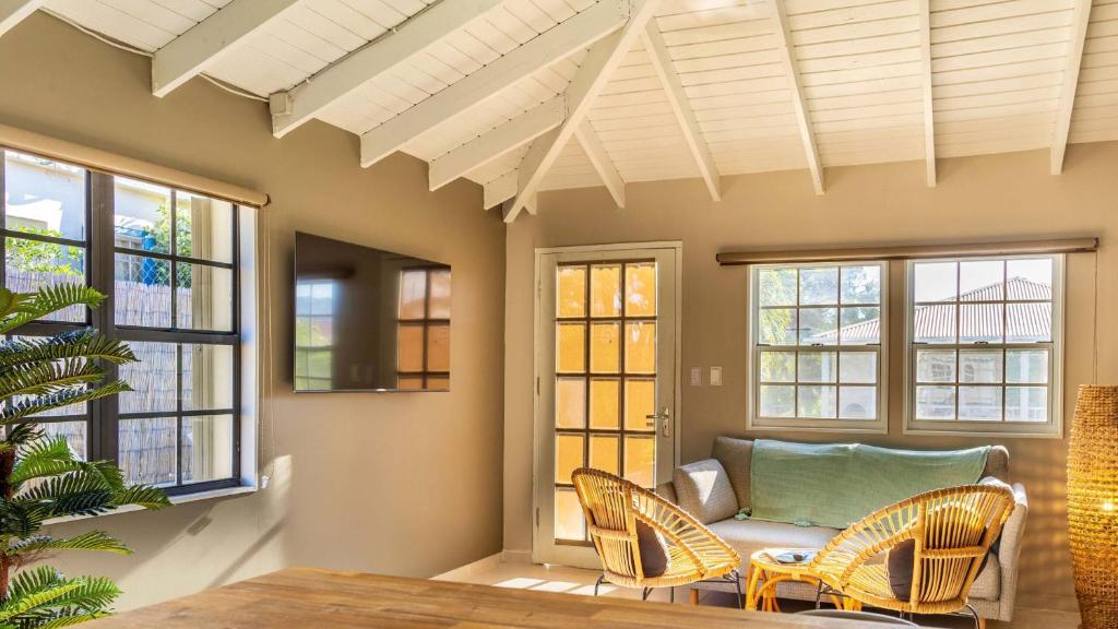 a living room with a couch and chairs and windows at Talk of the Town Inn & Suites - St Eustatius in Oranjestad