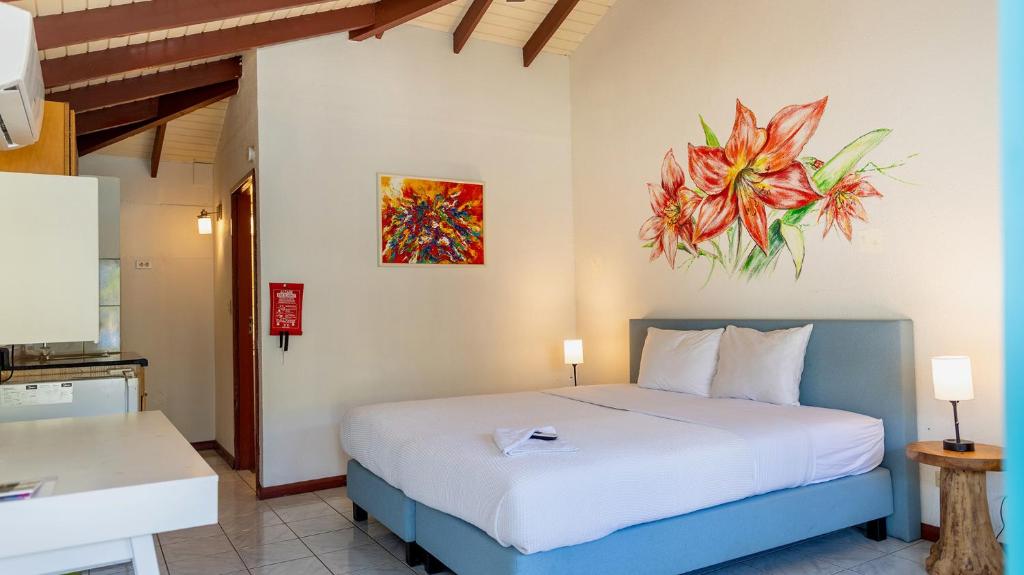 a bedroom with a bed and a painting on the wall at Talk of the Town Inn & Suites - St Eustatius in Oranjestad