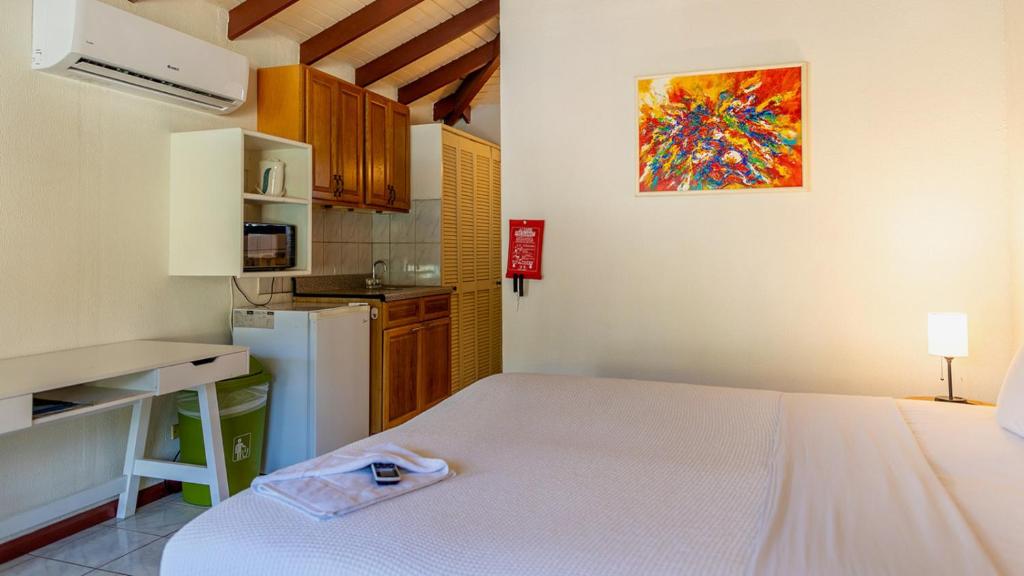 a small kitchen with a white bed in a room at Talk of the Town Inn & Suites - St Eustatius in Oranjestad
