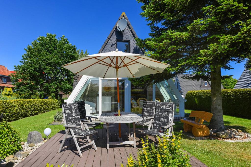 a table and chairs and an umbrella on a deck at Ferienhaus Boje 13 in Neuharlingersiel