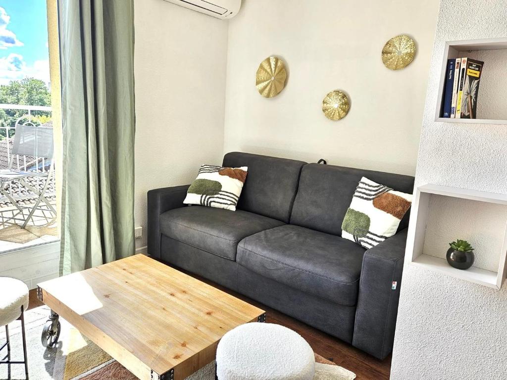un salon avec un canapé noir et une table dans l'établissement T2 neuf - centre - Parking supp, à Toulouse