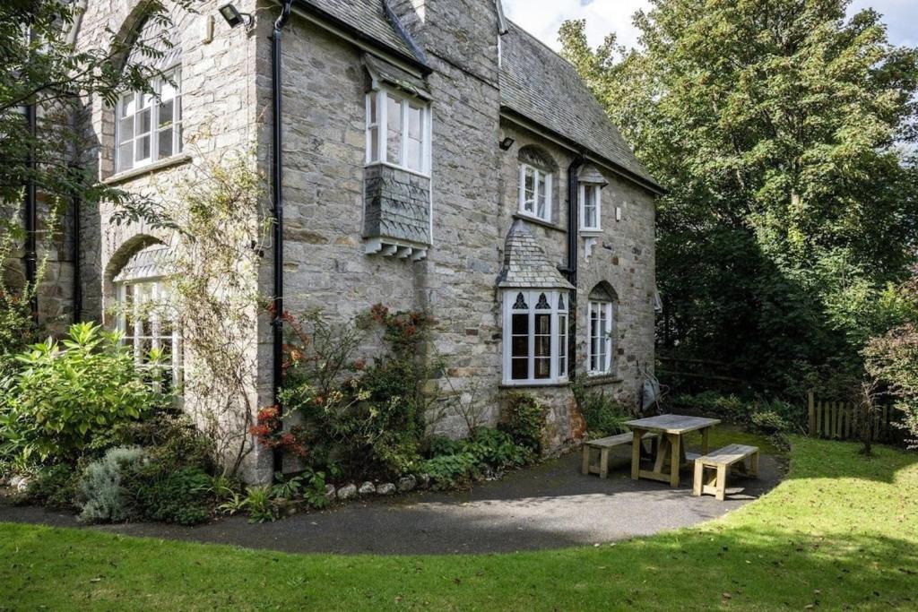 une ancienne maison en pierre avec un banc devant elle dans l'établissement Large Grade II Listed House & Garden nr Beaches, à Saint Columb Major