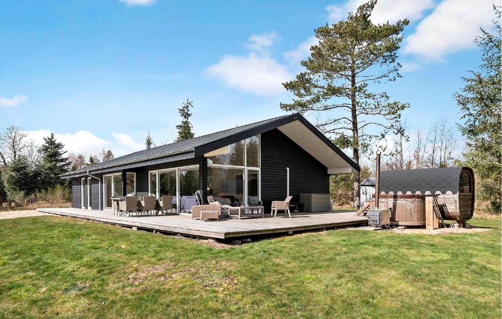 a black house with a deck and chairs on it at 4 Bedroom Stunning Home In Bording in Bording Stationsby