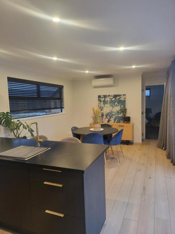 a kitchen and living room with a table and chairs at Kotuku Cottage in Tauranga