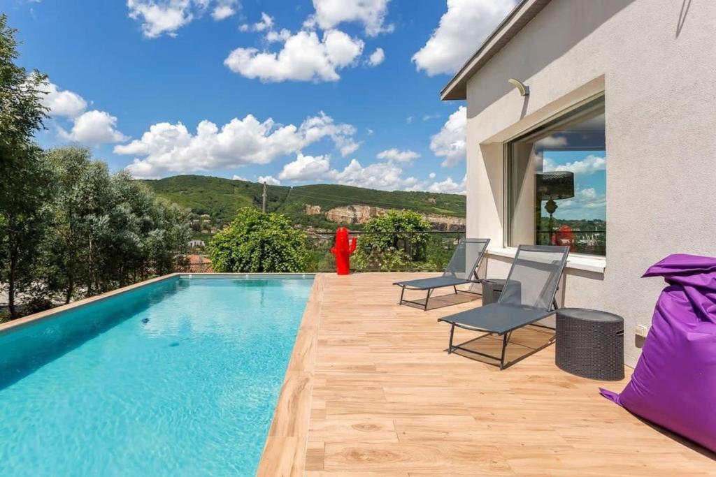 - une piscine avec 2 chaises à côté d'un bâtiment dans l'établissement House with swimming pool near Lyon, à Rochetaillée