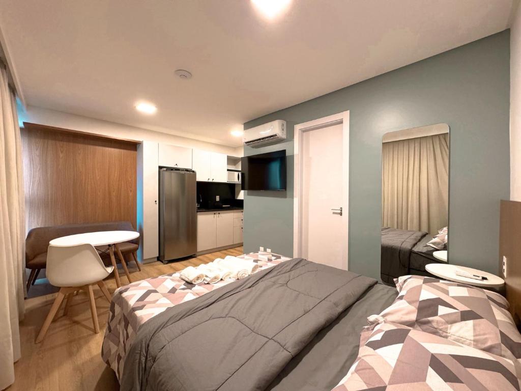 a bedroom with a large bed and a kitchen at Loft Studio com Piscina em Blumenau ZW3837 in Blumenau
