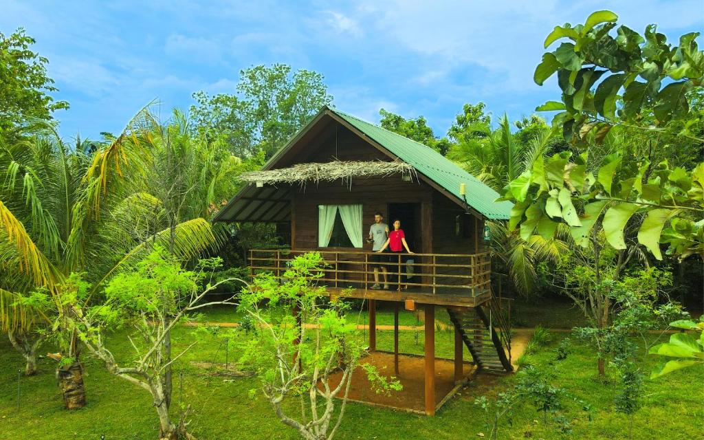 a couple standing on the porch of a house at Chena Huts Eco Resort in Sigiriya