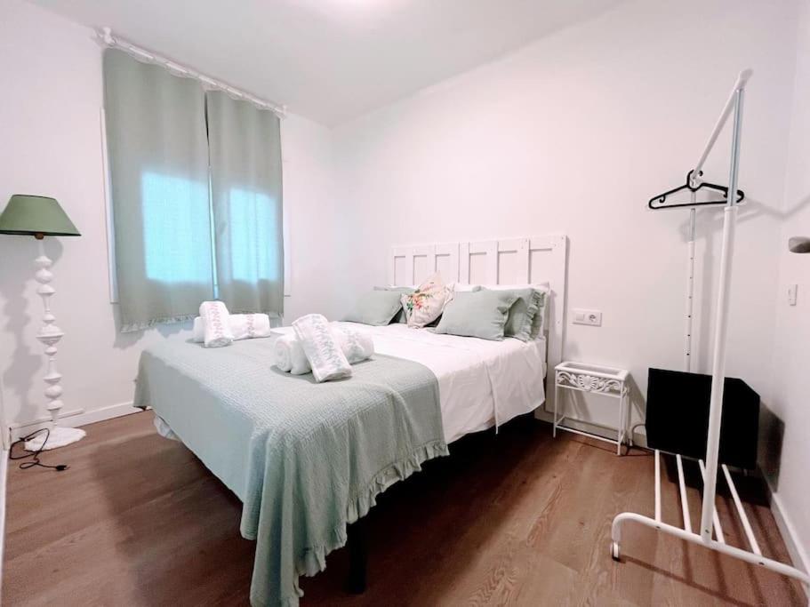 a white bedroom with a bed and a window at Casa Mary independiente céntrica con terraza cubierta in Porriño