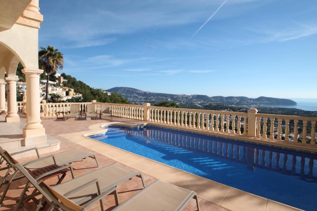 a view of a swimming pool on a balcony with chairs at Mimo - sea view villa with private pool in Moraira-Teulada in Moraira