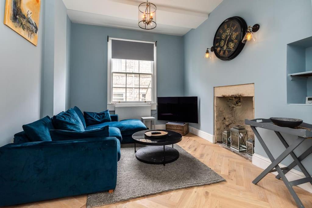 a living room with a blue couch and a fireplace at Charming Cottage - Country Views in Bath