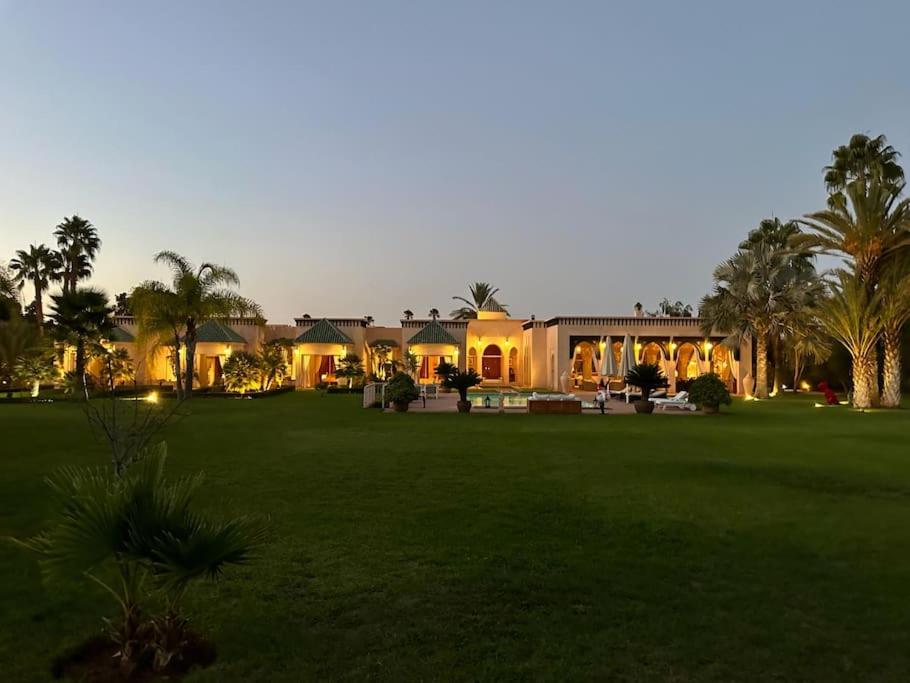 a house with a green yard with palm trees at Villa Alcázar Marrakech in Had Abdallah Rhiat