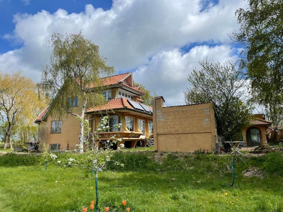 an old house on a hill with a grass field at Særpræget & teatralsk villa, med skøn udsigt in Borre