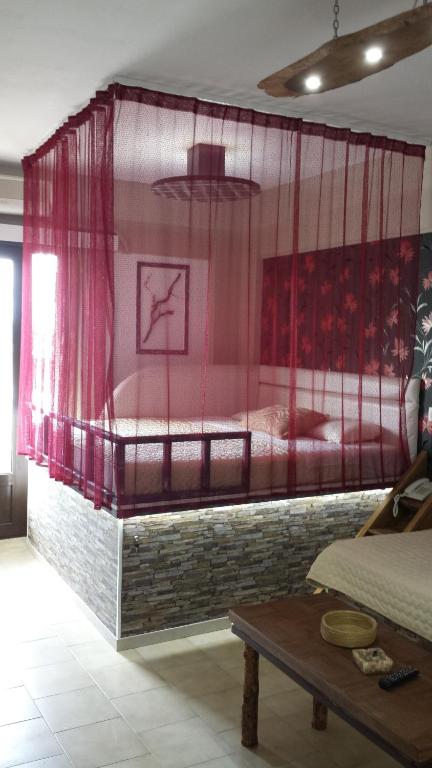a bedroom with a bed with pink curtains and a table at Takis Hotel Apartments in Ialysos