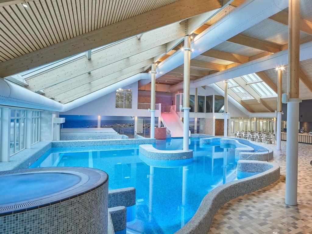 Una gran piscina con agua azul en un edificio. en Chalet in Texel by the Dunes & Water, en De Cocksdorp