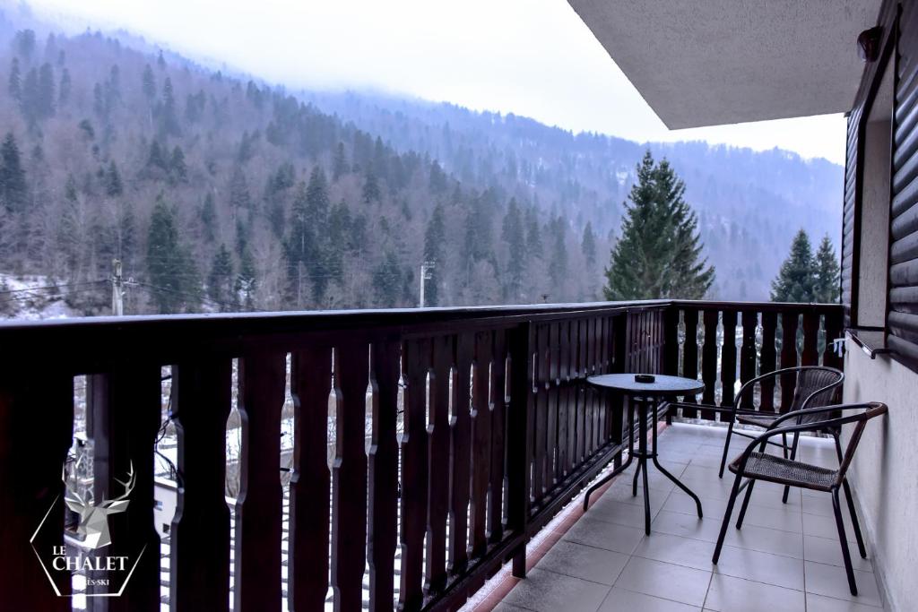 a balcony with a table and chairs and a mountain at Pensiunea Noni in Azuga