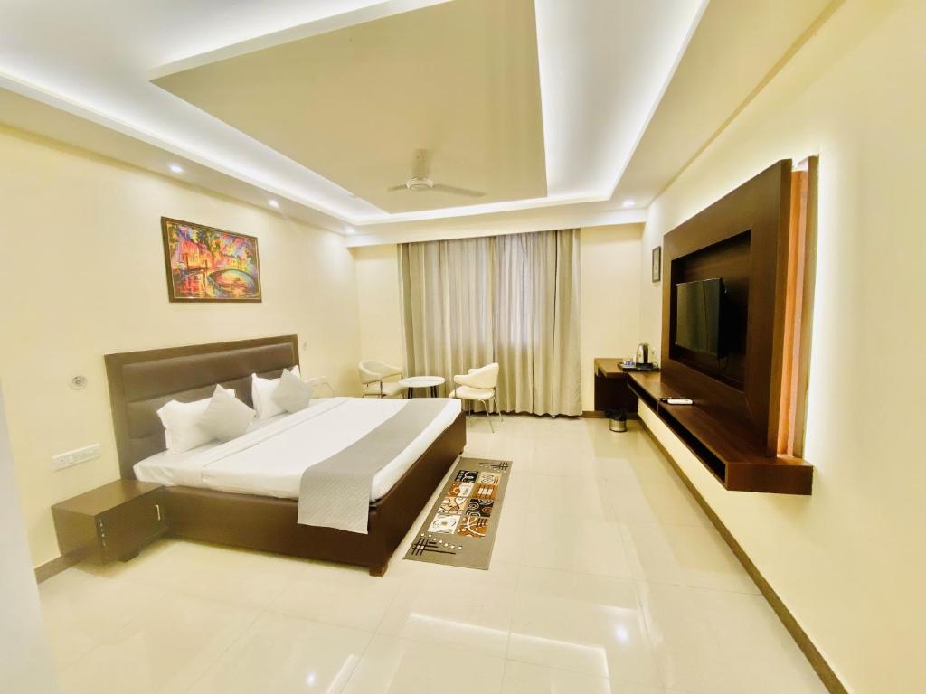 a hotel room with a bed and a flat screen tv at Ayansh Klyde Inn, Lucknow in Lucknow