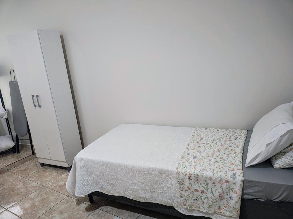 a bedroom with a bed and a white wall at Residencial Carvalho Ap 4 in Torto