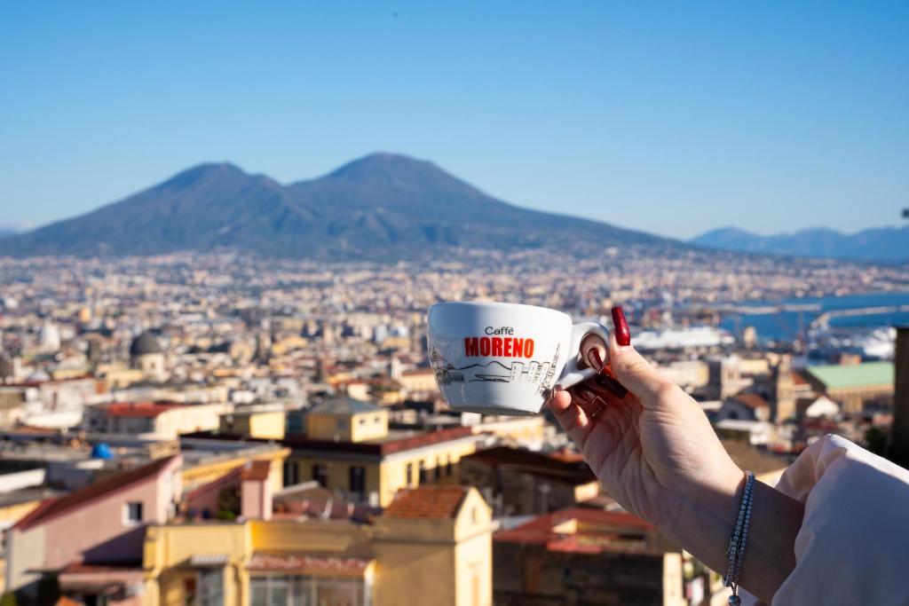 a person holding up a coffee cup in front of a city at NA bella vista Rooftop-B&B in Naples