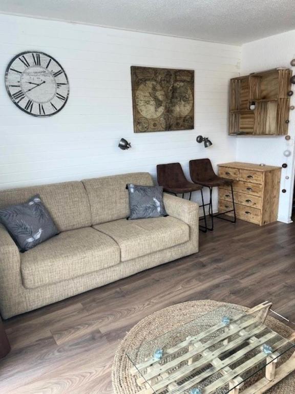 un salon avec un canapé et une horloge au mur dans l'établissement Résidence Panoramic B - studio cabine 4 personnes MAE-7371, à Orcières