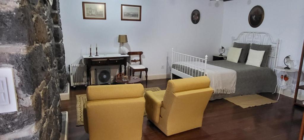 ein Schlafzimmer mit einem Bett und zwei gelben Stühlen in der Unterkunft Refúgio do Santa in Calheta