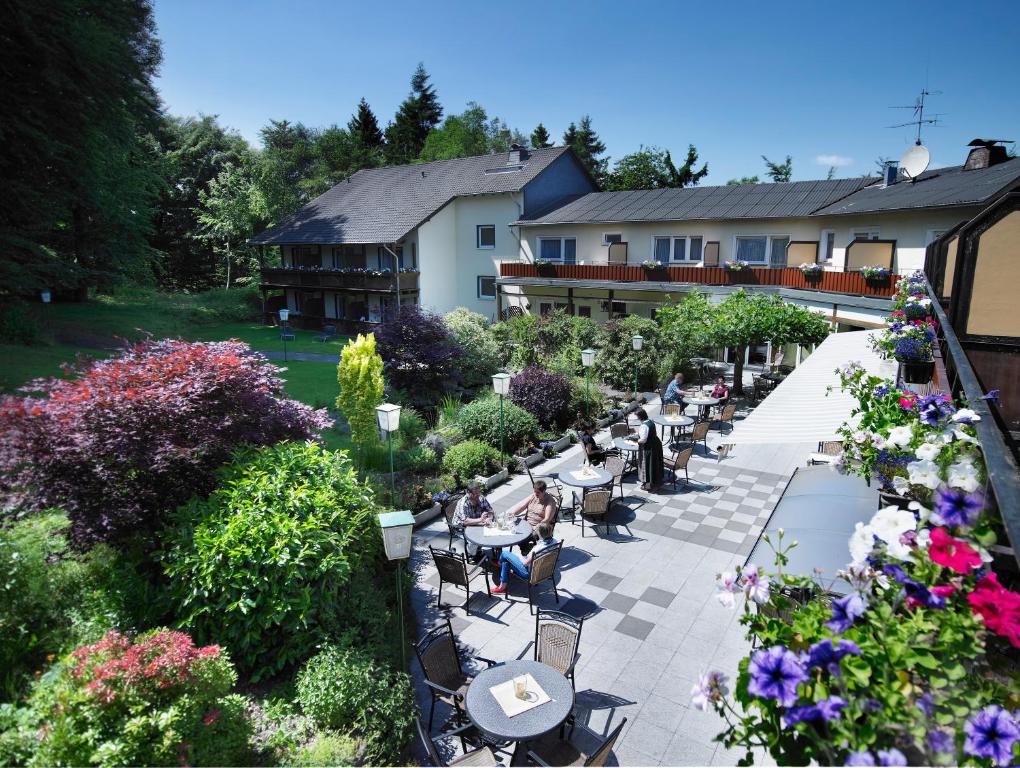 eine Außenterrasse mit Tischen, Stühlen und Blumen in der Unterkunft Waldhotel Kurfürst in Kaisersesch