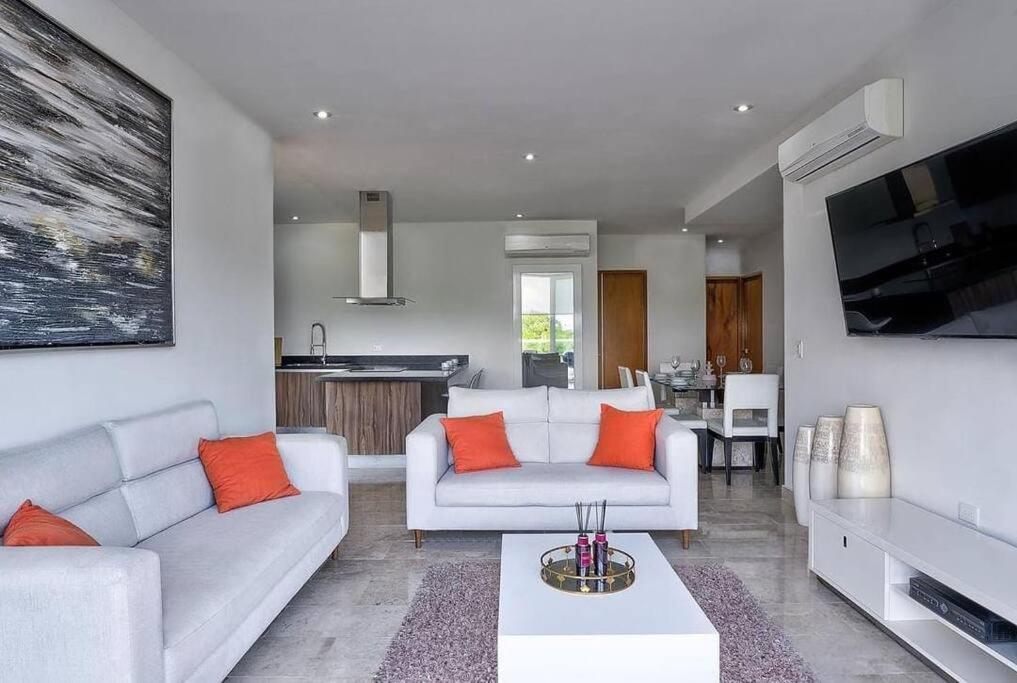 ein Wohnzimmer mit einer weißen Couch und orangefarbenen Kissen in der Unterkunft Penthouse with Beach Acces and Golf course in Akumal