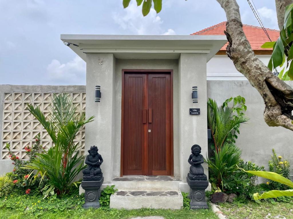 une maison avec une porte rouge et quelques plantes dans l'établissement Luana Villa Ubud, à Ubud