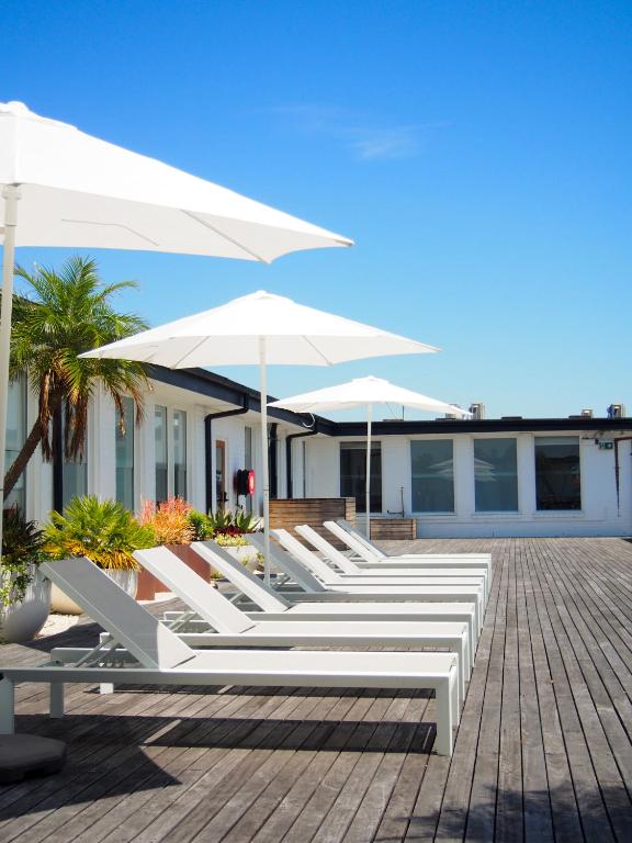 a row of white lounge chairs and umbrellas at Barrys Beach Road Hotel in Sydney