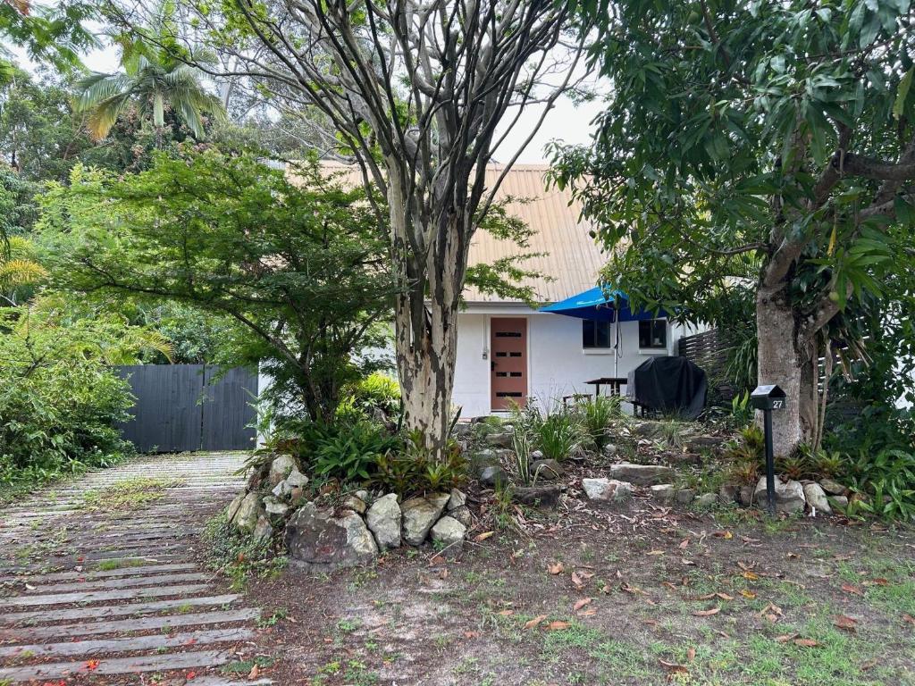 ein Haus mit einem Baum neben einer Einfahrt in der Unterkunft 27 Green Valley Drive - Rainbow Beach. Beach Chalet. Pets welcome in Rainbow Beach