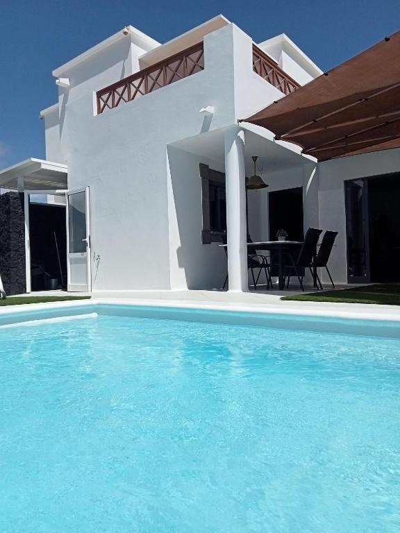 a white house with a swimming pool in front of it at Villa Lanzarote Zen in Playa Blanca