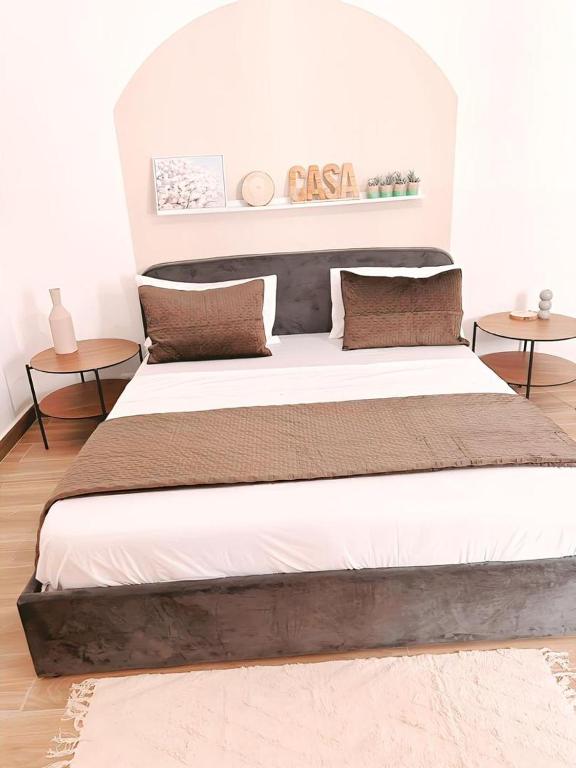 a large bed in a room with two tables at Cosy Mamelles in Dakar