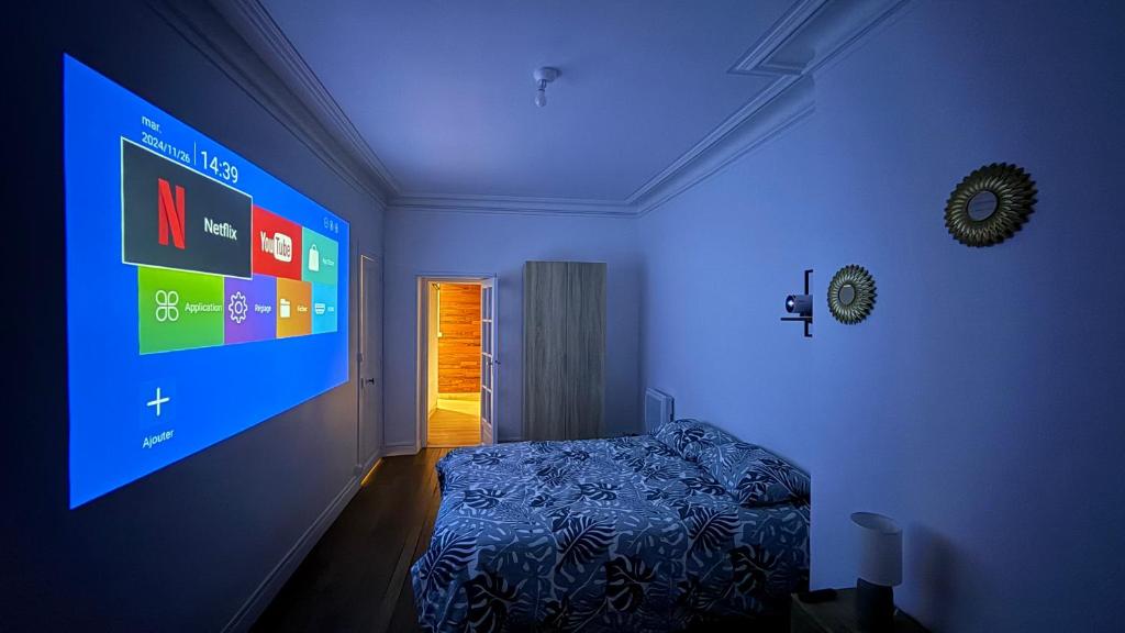 Cette chambre comprend un lit et un grand écran. dans l'établissement Le carmes - Rétroprojecteur - Hypercentre Orléans, à Orléans