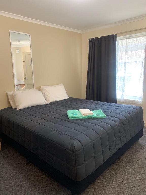 a bed with two towels on top of it in a bedroom at Mid Coast Motor Inn in Macksville
