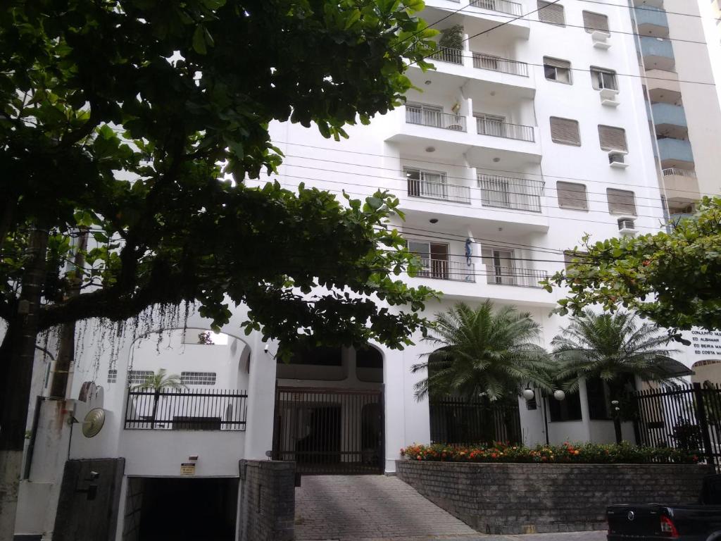 a large white building with trees in front of it at Apartamento Pitangueiras Guarujá in Guarujá