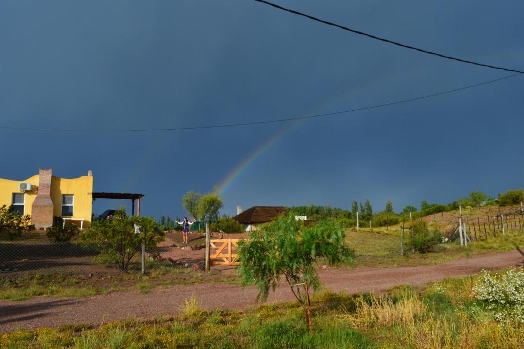 un arco iris en el cielo sobre una casa con un camino de tierra en Cabaña Andalue en San Rafael