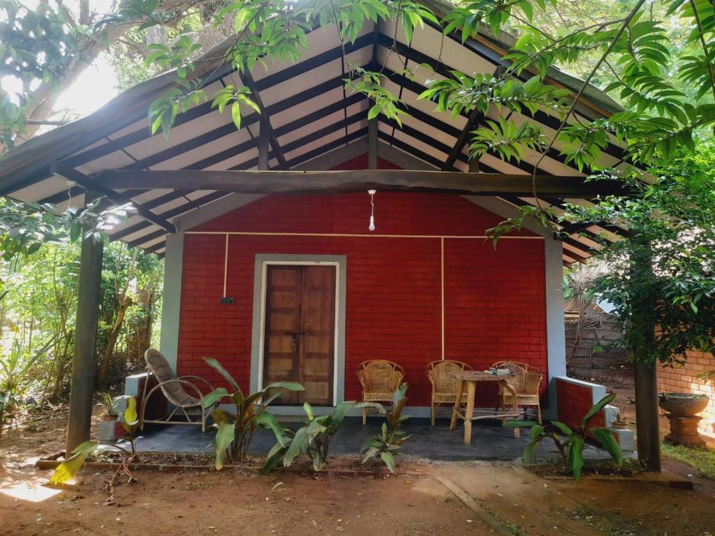 une maison rouge avec une table et des chaises devant dans l'établissement Sandalwood Family Cottages, à Uda Walawe