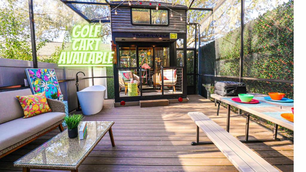 a patio with a couch and tables on a building at FunTropicalTinyHomeGolfCartLake in Orlando