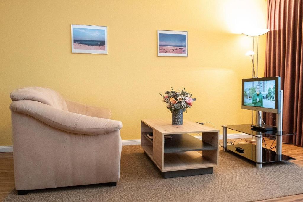 un salon avec une chaise et une télévision dans l'établissement Haus-Ornum-1-OG-O-Wohnung-13, à Westerland