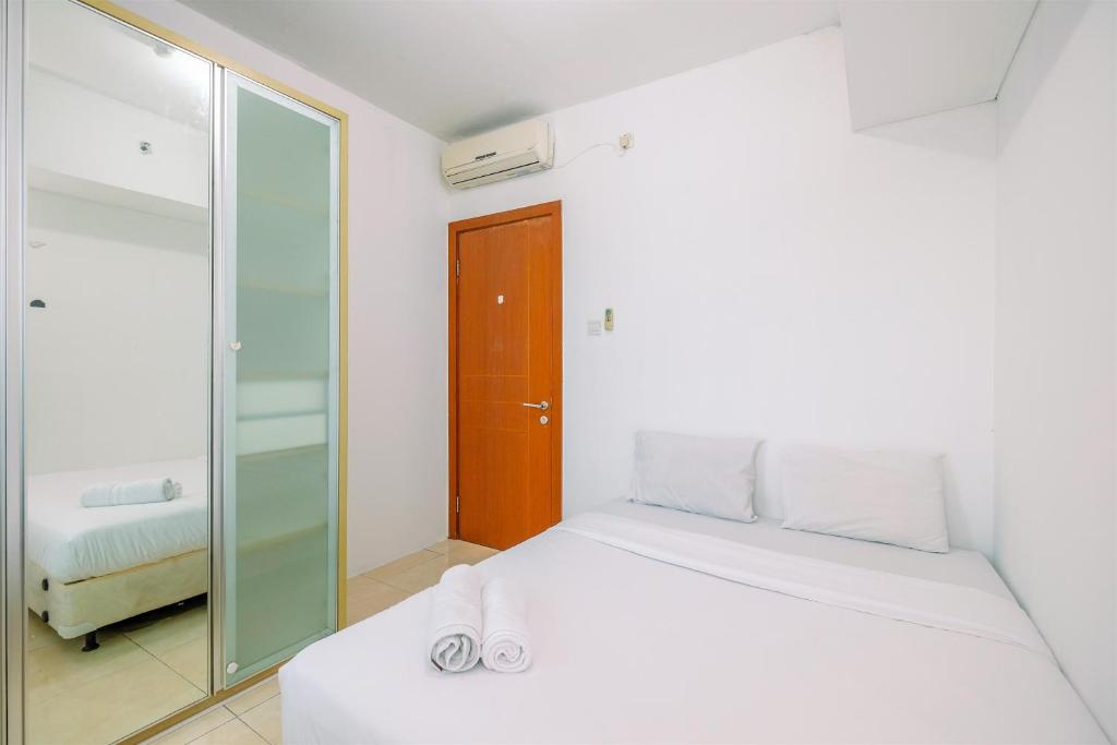 a white bedroom with a bed and a mirror at Spacious 2BR Apartment at MT Haryono Square By Travelio in Jakarta