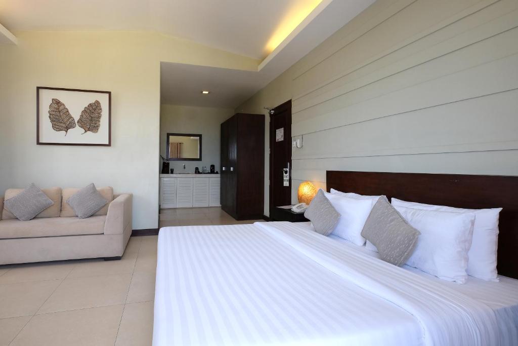 a bedroom with a large white bed and a couch at Alba Uno Hotel in Cebu City