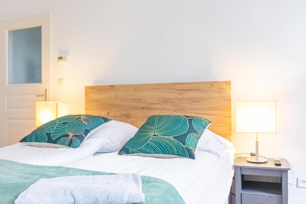 two beds with green and white pillows in a bedroom at Convenient 3-BR Shared Apt, 15 Min to Landstraße Hub in Vienna