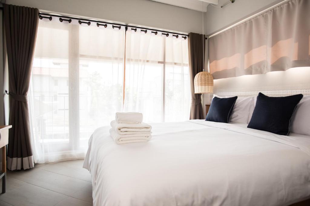 um quarto com uma cama branca e toalhas em Thapae Happy House em Chiang Mai
