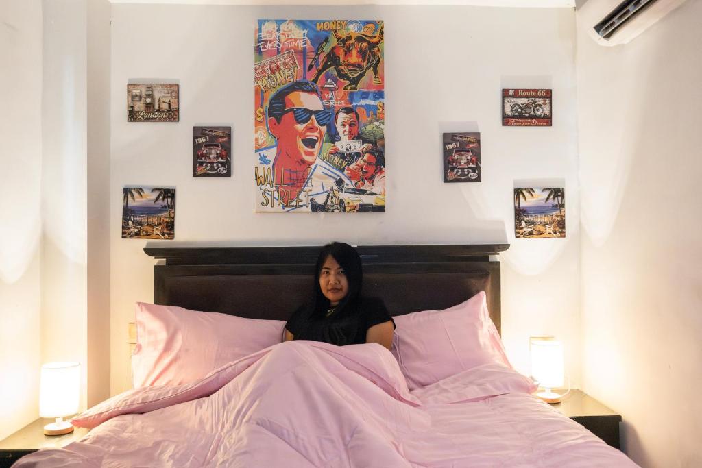 a woman sitting in a bed in a bedroom at Abunawas Merry Inn at Walking Street in Pattaya South