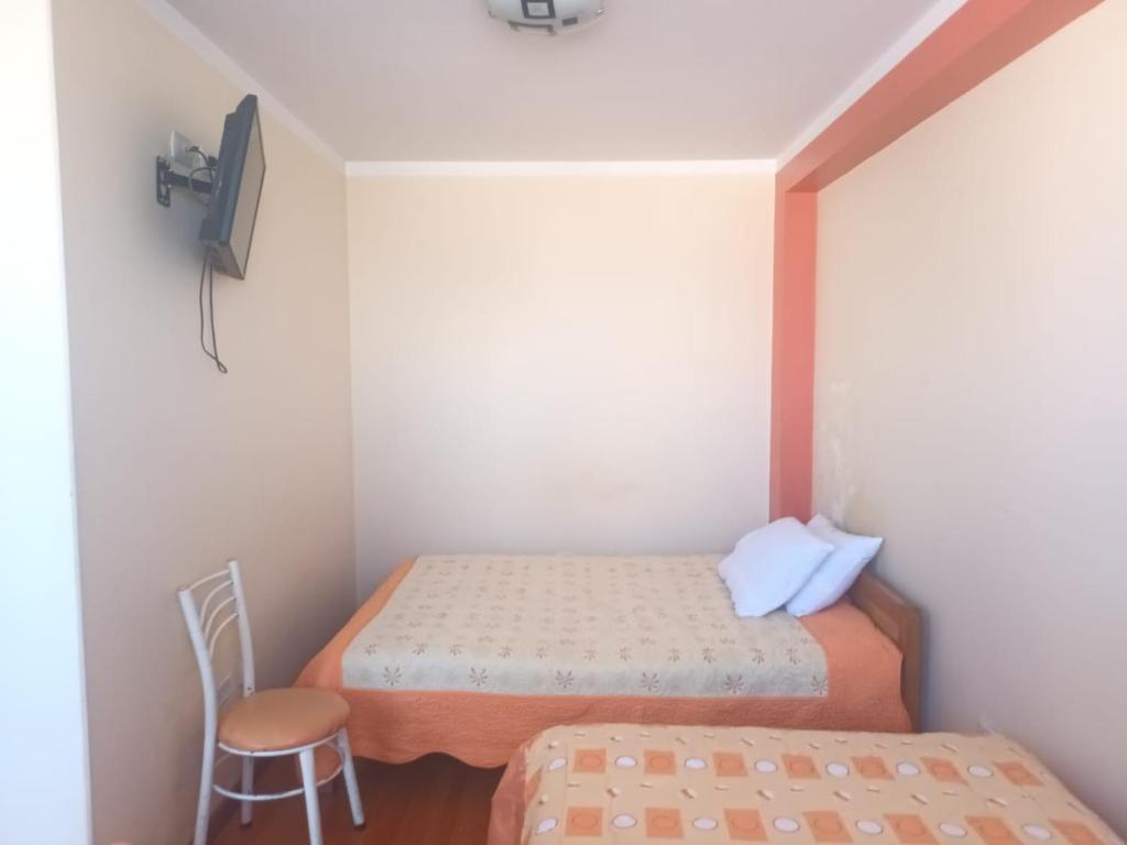 een kleine kamer met 2 bedden en een stoel bij Hospedaje Vista al Lago in Puno