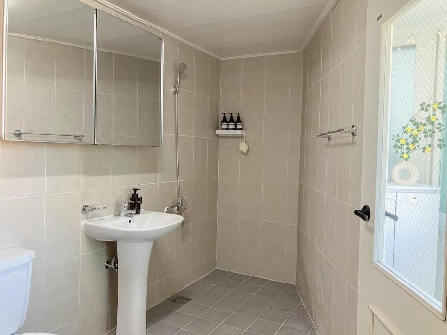 Un baño blanco con lavabo y ducha. en Pin Lights, en Seúl